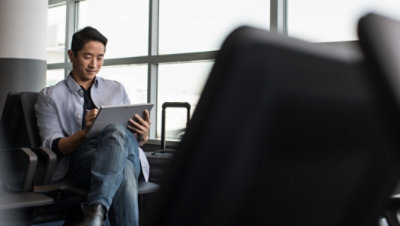 Personne assise dans un aéroport et utilisant un stylet et une tablette
