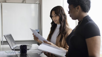 Dos personas conversan mientras observan papeles