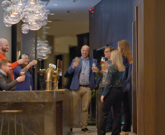 Personas levantando sus vasos para brindar en un bar de Carlsberg
