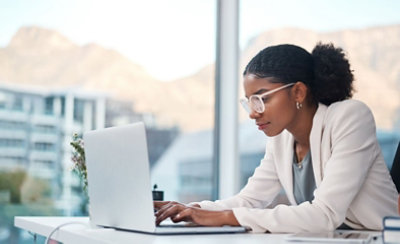 Una persona sentada en su escritorio escribe en un portátil.
