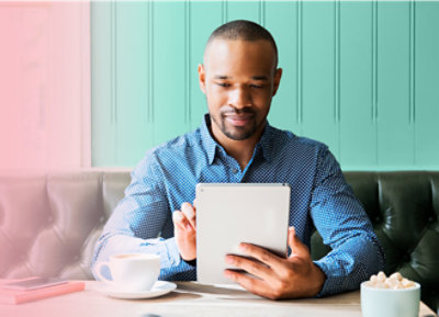 Una persona sentada y usando su tableta con café en su mesa