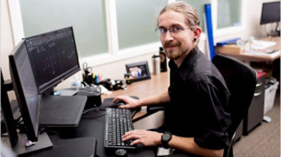 En person som arbetar vid ett skrivbord och ler