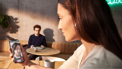 A woman is taking a picture of her friend on her phone.