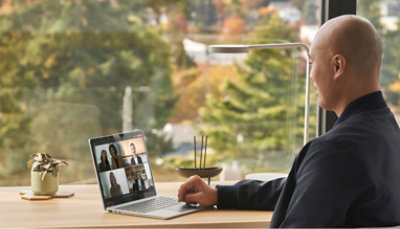 A man is sitting at a desk using a laptop.