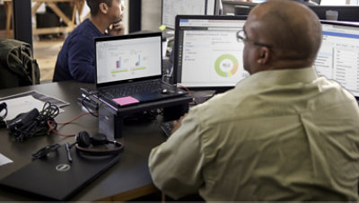 A person wearing glasses working with multiple screens