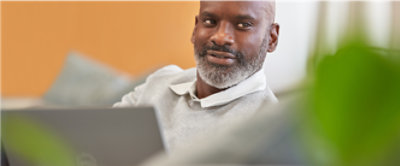 Una persona sonriendo con una computadora portátil colocada frente a él.