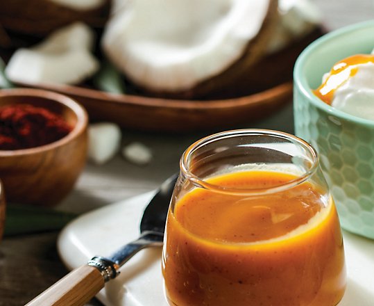 A bowl of sauce with ice cream and coconuts.