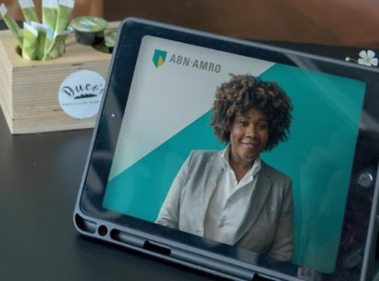 A man is sitting at a table with a tablet in front of him.