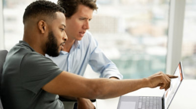 Zwei Personen sehen auf einen Laptop und zeigen auf den Bildschirm