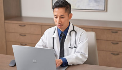 A medical professional typing on a laptop.