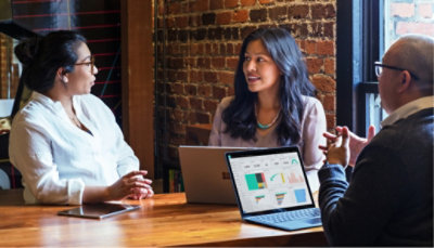 Three people having a conversation at a table in a cafe.