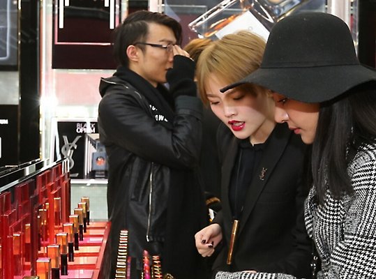 店の中で多数の香水のびんを見ている人々。