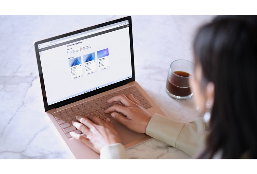 صورة لسيدة تكتب على جهاز كمبيوتر محمول يعرض الصفحة الرئيسية لـ Windows 365