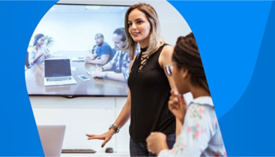 Personer i et mødelokale i et videomøde med personer, der sidder rundt om et bord i et andet rum