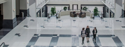 Geschäftsleute, die in einem modernen Bürogebäude zu Besuch sind bzw. dort gemeinsam unterwegs sind.