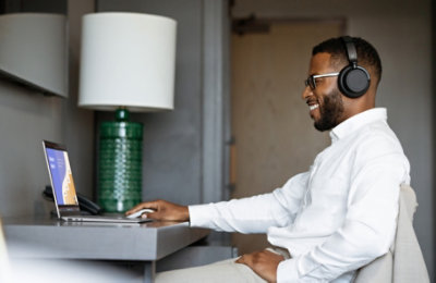 Eine Person mit Kopfhörern, die auf einem Laptop eine PowerPoint-Präsentation ansieht