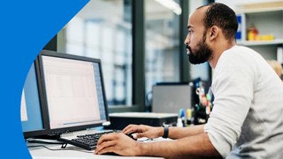 Una persona sentada frente a su escritorio trabajando con múltiples pantallas.