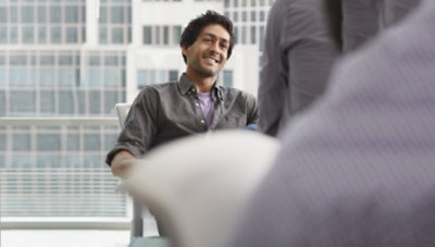 Personne assise participant à une réunion et souriant.