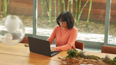 Personne assise à une longue table en bois et travaillant sur un ordinateur portable