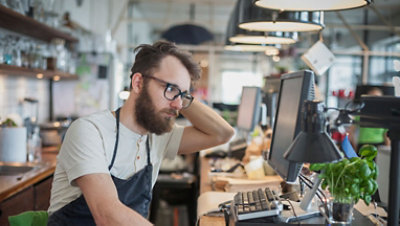 A restaurant cashier looks at a desktop screen