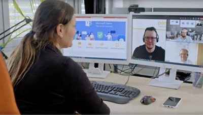 A woman in a video conference watches a monitor screen