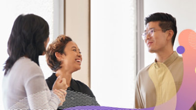 Tre personer diskuterar och ler på kontoret