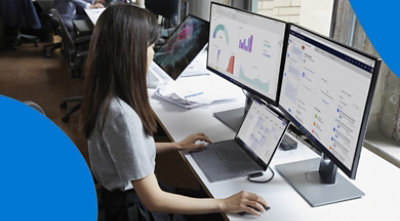 A person working at their desk with multiple screens.