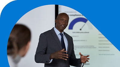 Quatre personnes discutant assises à une table de conférence avec des ordinateurs portables et des tablettes