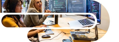 两个人坐在桌子旁，看着一台链接到两台桌面显示器的笔记本电脑 