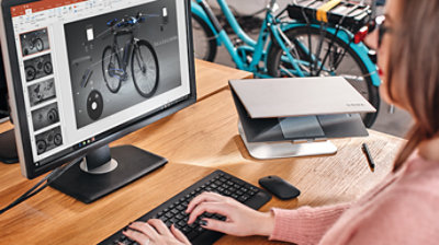 Oseba sedi za mizo in ustvarja PowerPointovo predstavitev