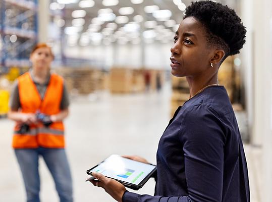 En person som holder et nettbrett som snakker til arbeidere med sikkerhetsvester