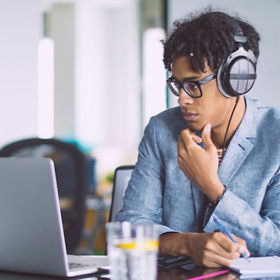 Een persoon die een laptop en een hoofdtelefoon gebruikt