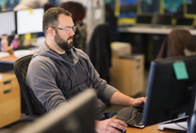 An IT pro working at a desk in an open office area