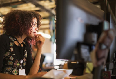 a person seated at a desk in an office looking at a monitor