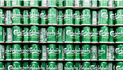 Rows of green Carlsberg Denmark cans are stacked tightly on store shelves.