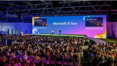 A large audience watches speakers on stage at a Microsoft AI Tour event.