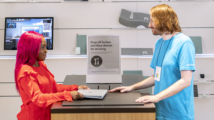 Microsoft Store associate helping customer with their Surface device.
