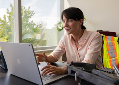 A woman smiling at a laptop.