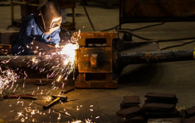 Welder in protective gear cutting metal in an industrial workshop as sparks fly
