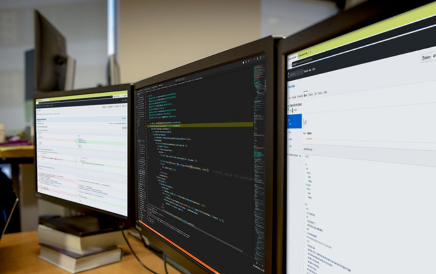 Three computer screens side by side with code displayed.