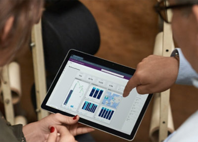 Two people are looking at a tablet screen displaying data charts and graphs. 