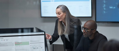 A person in a suit pointing at a computer screen