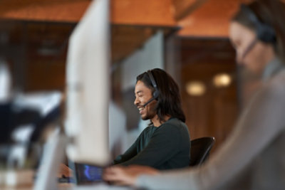 Kaksi ihmistä työskentelee toimistossa kuulokkeet päässä.