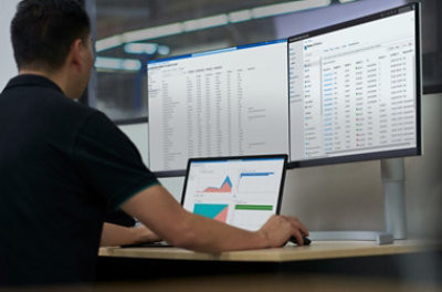 Ein Mann, der an einem Desktop arbeitet und auf mehrere Bildschirme blickt.