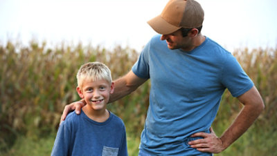 A farmer and his son in a corn field