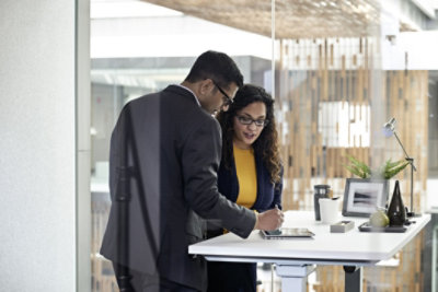 Female and male enterprise employees collaborating in an open office space, working on an HP Elitebook device, using a stylus pen.