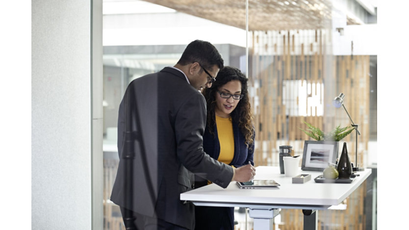 Female and male enterprise employees collaborating in an open office space, working on an HP Elitebook device, using a stylus pen.