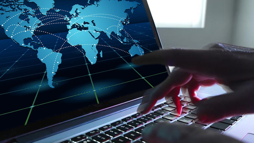 Hands typing on a laptop with a digital world map and global network connections on the screen.