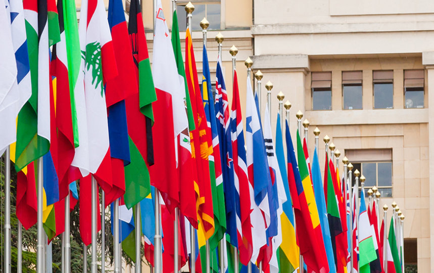 A row of international flags displayed outside a government or diplomatic building.