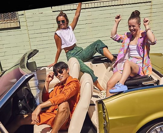 Drie personen die in een cabriolet zitten en crocs dragen